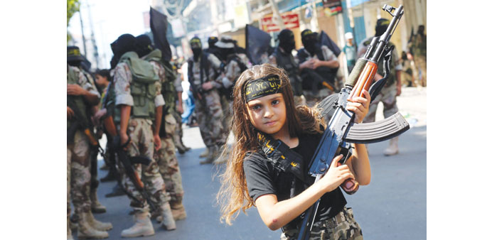 A girl holds a Kalashnikov as fighters of Al Quds Brigades, the military wing of Islamic Jihad, parade in Gaza City yesterday.