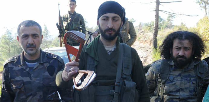 Deputy commander in a Syrian Turkmen brigade (C), holds handles believed to be parts of a parachute of the downed Russian warplane