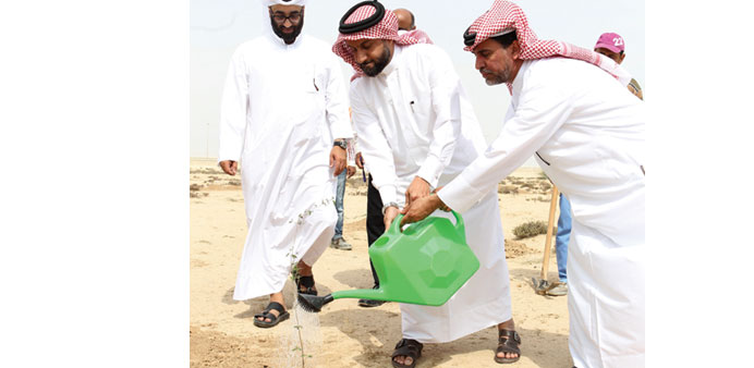 Yousef Khalid al-Khulaifi(centre) watering a sapling after planting it yesterday. PICTURES: Othman al-Samarraee