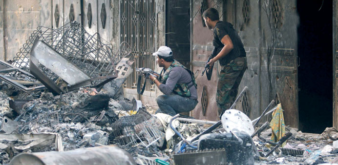 Free Syrian Army fighters take up position along a street filled with debris in the Sheikh Maksoud area of Aleppo yesterday.