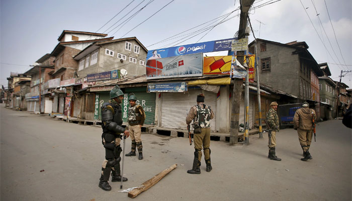 Indian security personnel stand guard along a deserted street during restrictions in Srinagar. Reuters