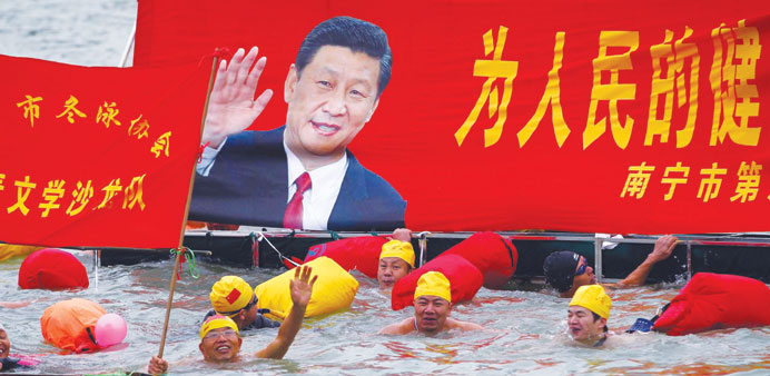 People swim with a banner featuring a portrait of Xi Jinping, Chinau2019s top leader, during a gathering to celebrate the new year in Nanning in south Chi