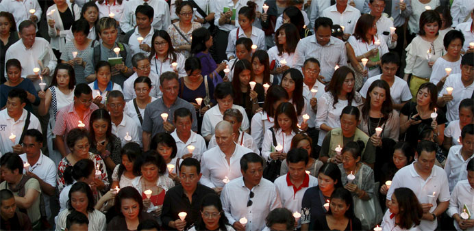 People light candles for victims during a march to the Erawan shrine