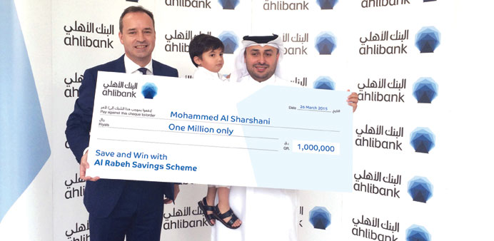 Muayed Mohamed al-Sharshani and his son, Hassan, receiving a cheque for QR1mn from an Ahlibank executive.