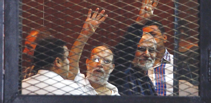 Essam El-Erian (left) and Mohamed Badie gesture from the enclosed dock during the trial session in Cairo yesterday.