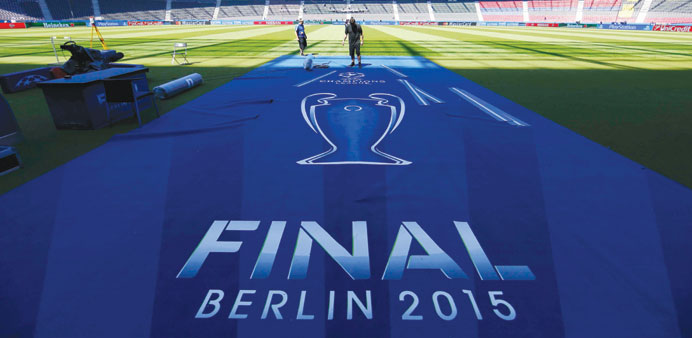 Workers prepare an UEFA Champions League final logo on the pitch at the Olympic stadium in Berlin where Juventus will play Barcelona in the final toda