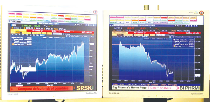 Computer screens show the evolution of Spainu2019s main stock index Ibex 35 (left), which has reached an 18-month high at 8,821 points and the risk premiu
