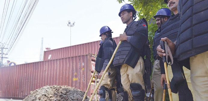 Pakistani policemen stand alongside a roadblock of shipping containers near the residence of cleric Tahir-ul-Qadri in Lahore yesterday.