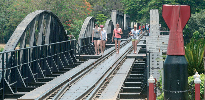 Foreign tourists walk on a railway bridge over the river Kwai built during World War II in Kanchanaburi province.