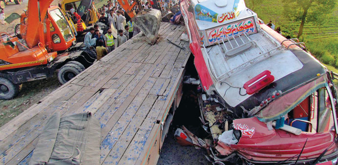 Pakistani rescuers use excavators to pull a tractor-trailer from a passenger bus after an accident in the town of Sukkur, 425km north of Karachi in th