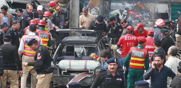Policemen and residents gather at the site of an explosion outside the police headquarters, in Lahore, yesterday.