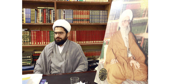 Sheikh Ali al-Najafi, spokesman for his father Grand Ayatollah Bashir al-Najafi (portrait), speaks during an interview in Najaf.