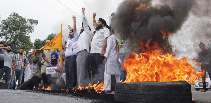 Members of Sikh community shout slogans against as they burn tires and block the Jammu-Pathankot national highway during a demonstration against the U