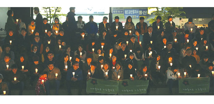 People take part in a candlelight vigil for missing passengers onboard the South Korean ferry Sewol in Ansan yesterday.