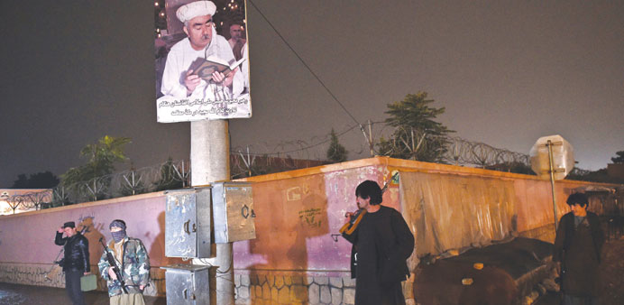 Armed Afghan residents stand guard under a poster bearing the image of a former vice-president, General Abdul Rashid Dostum during a patrol against th