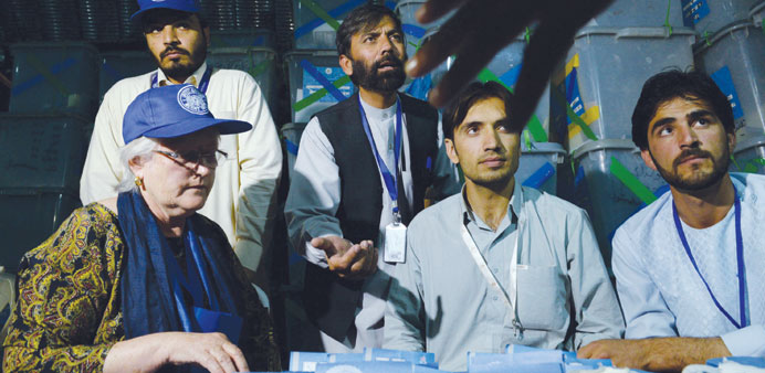 Afghan election commission workers and and a foreign observer sort ballot papers during an audit of the presidential run-off vote at a counting centre