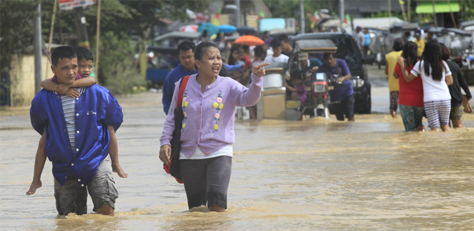 Residents wade through a flooded street after heavy rain at Candaba