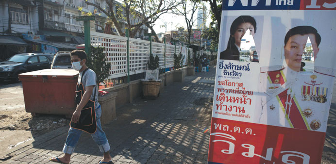 A man walks by a damaged election campaign poster of Thai Prime Minister Yingluck Shinawatra during a rally in Bangkok yesterday.
