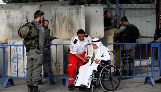 A wheelchair-bound Palestinian man is helped at an Israeli checkpoint as he makes his way to attend the first Friday prayer of the holy fasting month of Ramadan in Jerusalem's al-Aqsa mosque, in the West bank city of Bethlehem. Reuters