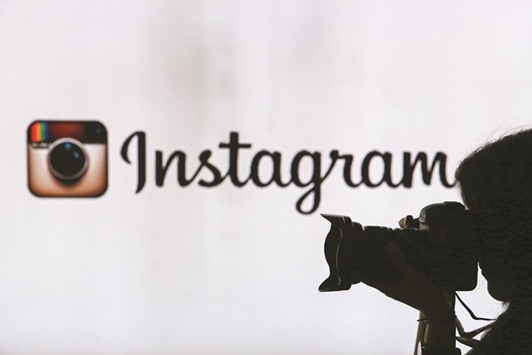 A woman takes a photograph against an illuminated wall bearing Instagram logo in London. Sixty-three percent of advertisers in the survey said they were most likely to use photo-sharing app Instagram, compared with 56% who said they would use social network Twitter.