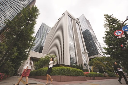 Pedestrians walk past the main branch of Bank of Tokyo-Mitsubishi UFJ in Tokyo. The banking giantu2019s move to consider quitting as one of 22 primary dealers is the latest sign of stress in a debt market thatu2019s struggling to cope with the Bank of Japanu2019s unprecedented monetary stimulus.