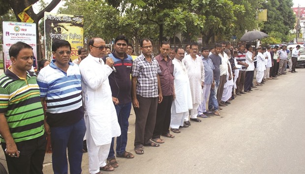 Bangladeshi men forming a human chain in protest against the killing of 62-year-old Hindu monastery worker Nityaranjan Pande, who was hacked to death in Pabna yesterday.