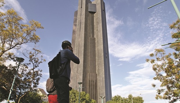 Pedestrians pass the headquarters of the South African Reserve Bank in Pretoria. The central bank on May 19 reduced its forecast for 2016 economic expansion to 0.6% as a slump in commodity prices and a drought hobble the economy.