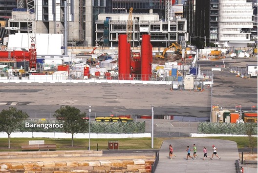Joggers run past a construction site in an area called Barangaroo located in central Sydney. From a year earlier, the Australian economy expanded 3.1%, compared with estimates for a 2.8% gain.