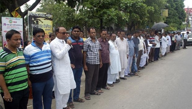 Bangladeshi men form a human chain in protest against the killing of 62-year-old Hindu monastery worker Nityaranjan Pande, who was hacked to death in Pabna on Friday. 