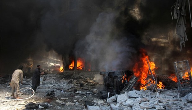 Men try to put out a fire at a market hit by air strikes in Idlib city, Syria