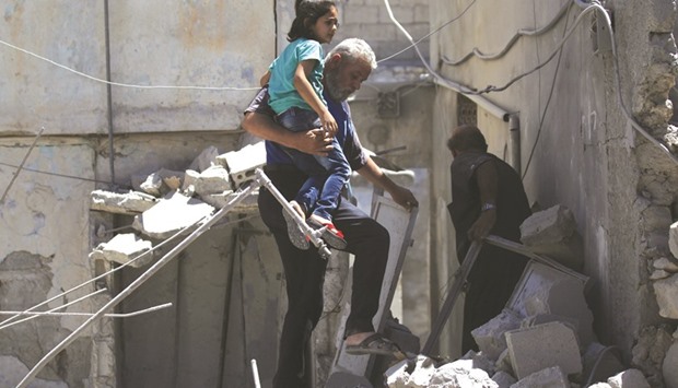 A man carries a girl as he makes his way through the rubble at a site hit by air strike in the rebel-controlled area of Maaret al-Numan town in Idlib province, Syria, yesterday.