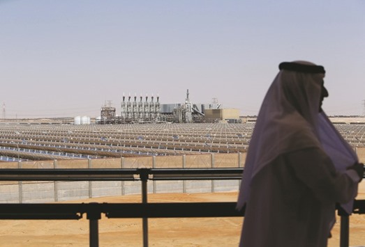An Emarati man stands on a balcony overlooking the Shams 1, Concentrated Solar power (CSP) plant, in Al-Gharibiyah district on the outskirts of Abu Dhabi (file). Wind and solar will be the cheapest forms of producing electricity in most of the world by the 2030s, according to BNEF.
