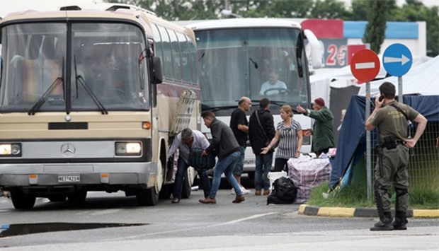 Migrants loads their belongings in a bus as they are evacuated from the makeshift camp