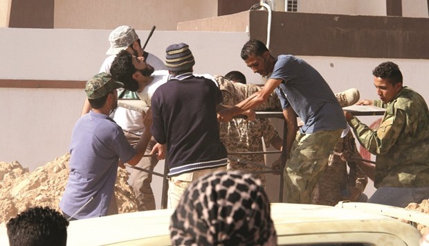 Forces loyal to Libyau2019s UN-backed unity government carry a comrade wounded during clashes with militants in Sirte as they take part in an operation to recapture the city from the Islamic State (IS) group.