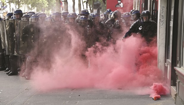 Red smoke rises from a smoke bomb near French anti-riot police during a demonstration against proposed labour reforms in Paris.
