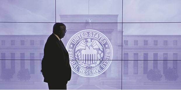 A security guard walks in front of an image of the Federal Reserve following the two-day Federal Open Market Committee (FOMC) policy meeting in Washington yesterday. Fed policymakers yesterday gave no indication of when they might raise rates, though their projections leave the door open to an increase next month.