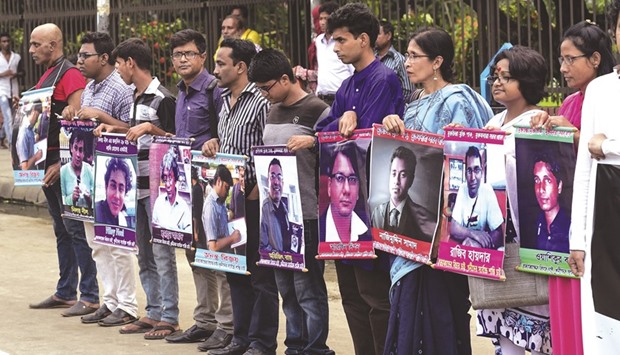 Activists holding the photos of activists, writers and bloggers who were murdered by unidentified assassins in the last few years, in Dhaka yesterday.