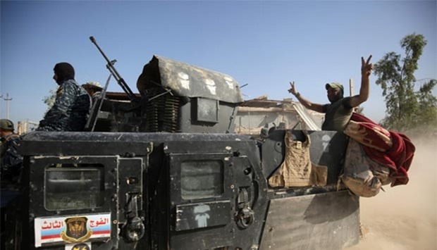 A member of Iraqi government forces flashes the victory sign in the back of an armoured vehicle during an operation in Fallujah's southern Shuhada neighbourhood to retake the area from the Islamic State.