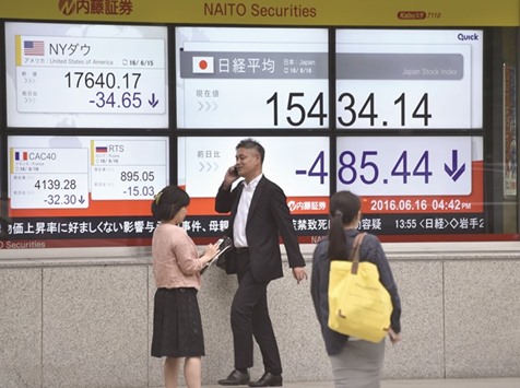 Pedestrians walk past an electronic indicator of the Tokyo stock market displayed on the window of a securities company. Japanu2019s benchmark stock index plunged more than 3% yesterday as the soaring yen hammered exporters after the Bank of Japan held fire on launching fresh stimulus.