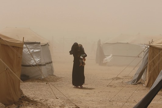  A woman, who fled Fallujah because of Islamic State violence carries her child during a dust storm at a refugee camp in Ameriyat Fallujah, Iraq.