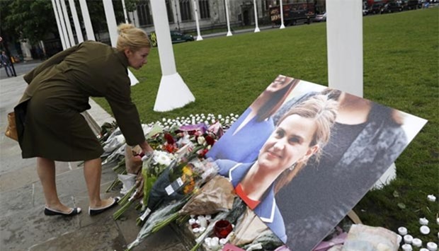 A woman leaves a floral tribute next to a photograph of murdered Labour Member of Parliament Jo Cox in Parliament Square, London, on Friday.