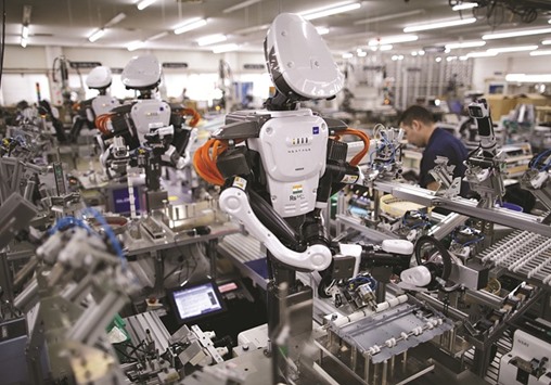 Humanoid robots work side by side with employees in the assembly line at a factory in Tokyo. Japanu2019s exports are expected to fall 10.4% last month from a year earlier, according to a Reuters poll yesterday.