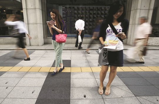 A pedestrian looks at an electronic board showing the various stock prices outside a brokerage firm in Tokyo. Japanese households put more money into stocks and mutual funds in the January to March quarter but the value of their assets fell for the first time in more than five years due to a stronger yen and weakening stock market, data showed yesterday.