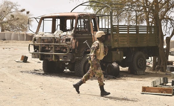 A Nigerian soldier walking near a damaged army vehicle at Bosso military camp yesterday following attacks by Boko Haram fighters in the region.