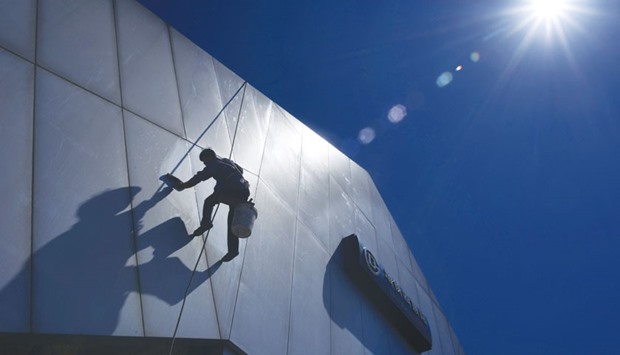 A worker cleaning the facade of a subway station entrance in Beijing. China has made recent progress in boosting labour productivity, encouraging technological innovation and improving service quality in key urban areas, despite severe financial repression and inadequate access to funding by small and medium-size private enterprises.