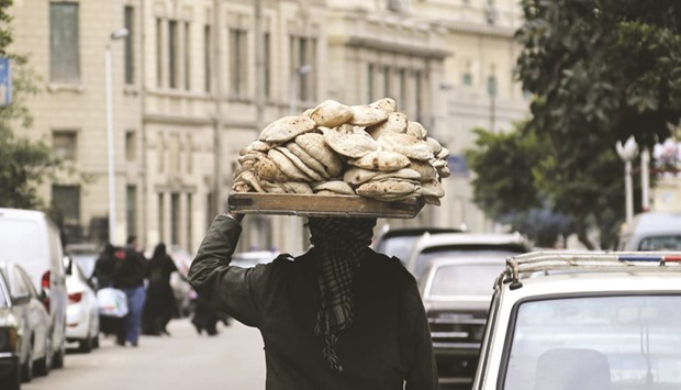 A man carries freshly baked bread on his head along a street in Cairo. Unnecessary and burdensome regulations will leave Egypt, the worldu2019s largest wheat buyer, with more than $860mn in direct costs and lost export earnings this year while its citizens pay more for their food, according to the US Department of Agriculture.