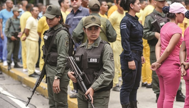 Venezuelan National Guards watch over inmates, whose identity was u2018misappropriatedu2019 by the opposition to sign a recall referendum against President Nicolas Maduro, demonstrate outside the Public Ministry building in downtown Caracas on Friday.