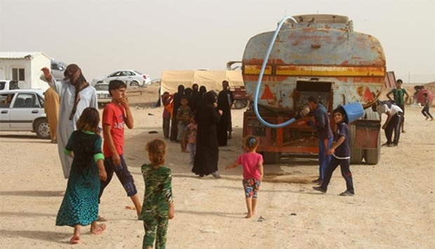 Displaced Iraqis from Fallujah wait for water to be delivered at a camp where they are taking shelter, some 18 kilometres from Ramadi.