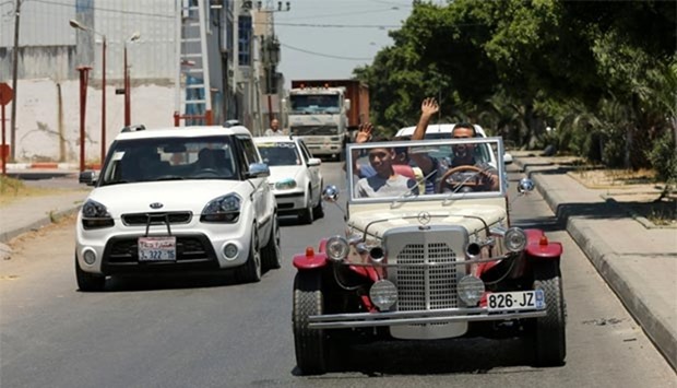 Palestinian Munir Shindi waves as he drives a replica of a 1927 Mercedes Gazelle that he built from scratch, on a street in Gaza City.