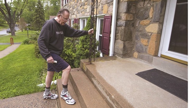 Philadelphia Inquirer sports columnist Bill Lyon, after his daily walk around his Broomall, Pennsylvania, neighbourhood, grabs onto a decorative support on his front stoop as he readies himself to climb the steps to the front door.
